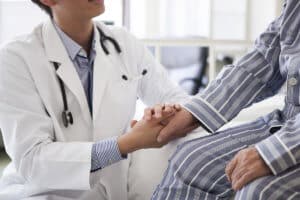 A doctor holds a patient's hand while telling them about an inpatient drug detox center