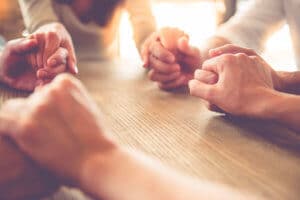 a group of people hold hands in prayer as a sign of faith