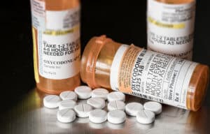 multiple prescription bottles with pills on the table show difference between opiate vs opioid