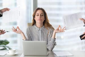 woman at a desk with a laptop doing a yoga pose. how to practice patience