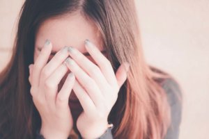 woman covering face with hands wondering what is psychological dependence