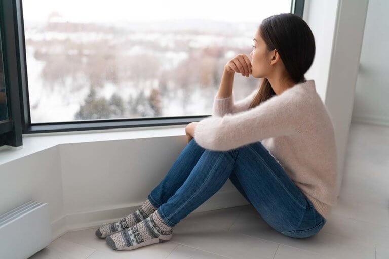 woman pensively looking out at a snowy landscape wondering what is lean drink aka purple drank